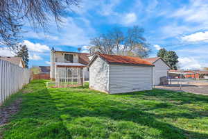 Rear view of house with a fenced backyard, an outbuilding, and a chimney