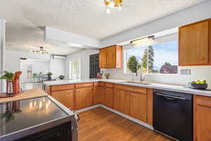 Kitchen featuring stainless steel electric range, dishwasher, wood finish cabinets, suspended lighting, and a textured ceiling