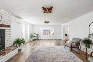 Living area with a fireplace, a textured ceiling, light wood-type flooring, and healthy amount of natural light