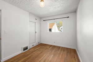 Unfurnished bedroom with hardwood / wood-style floors, a closet, and a textured ceiling