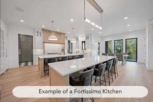 Dual tone kitchen featuring dual tone cabinets, glass fronted cabinets, light stone countertops, light wood finished floors, and a kitchen breakfast bar