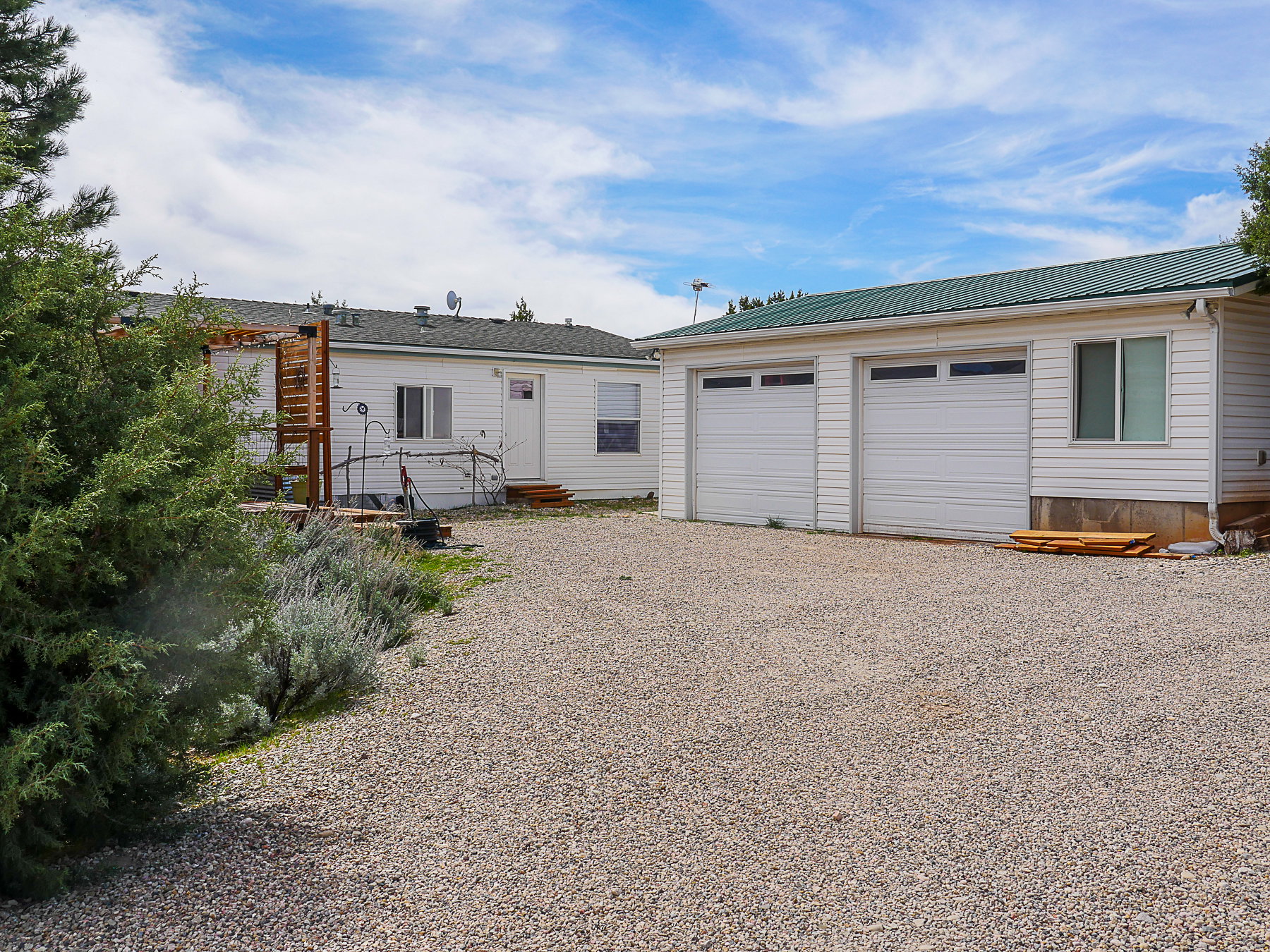 Back of house featuring a garage, a metal roof, an outbuilding, and gravel driveway