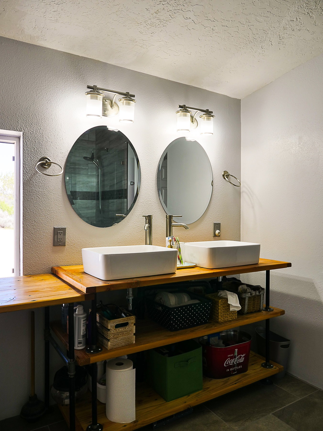 Bathroom with a textured wall, double vanity, a textured ceiling, and tiled shower