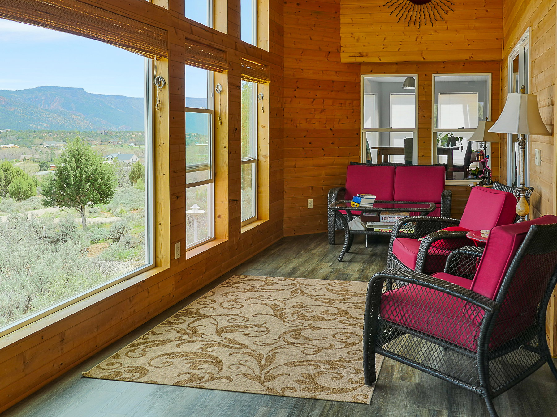 Sunroom / solarium with wooden walls, a mountain view, wood finished floors, and a high ceiling