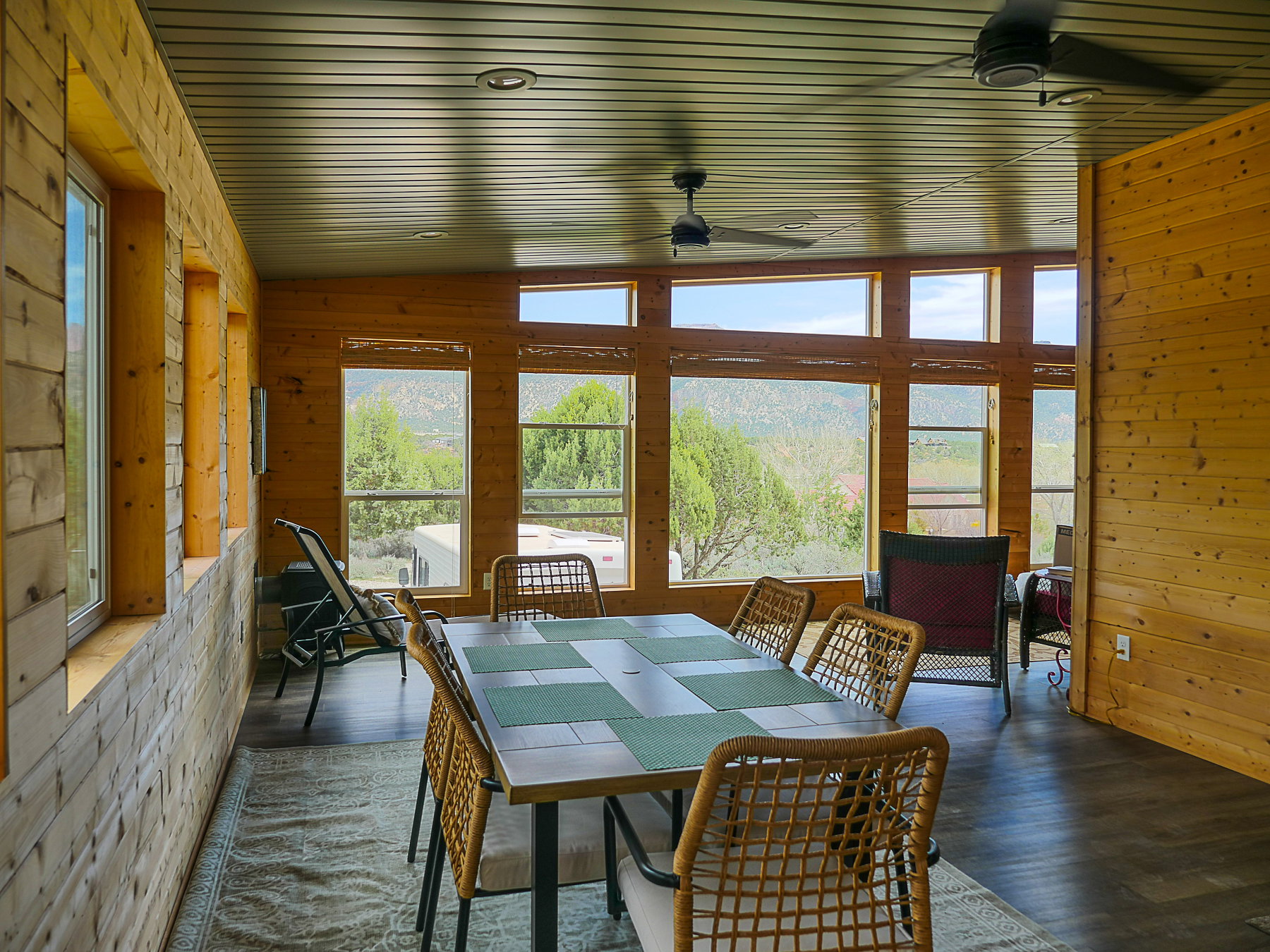 Dining room with wooden walls, lofted ceiling, a ceiling fan, and wood finished floors