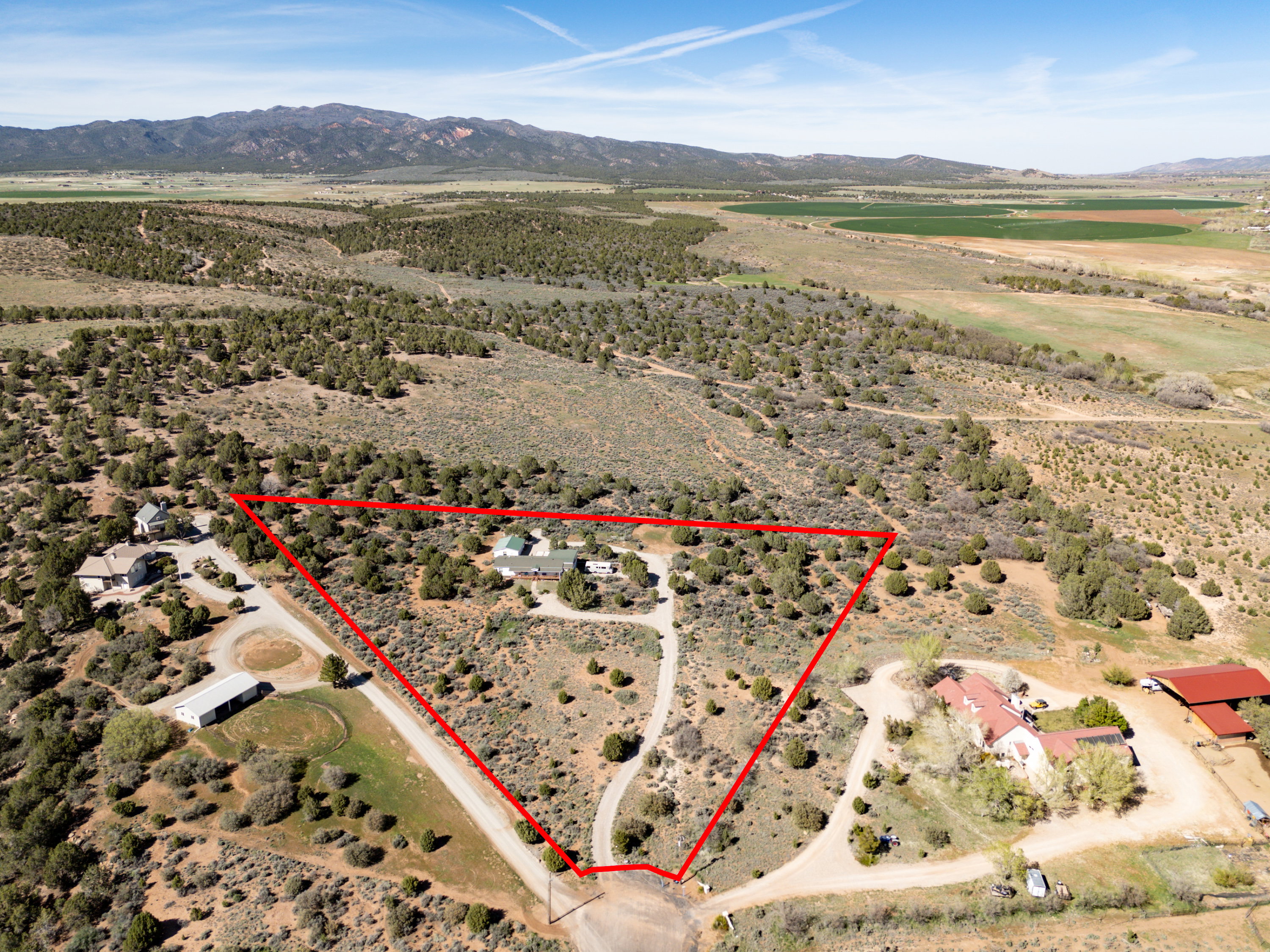 Overview of rural landscape with property parcel outlined and a mountainous background