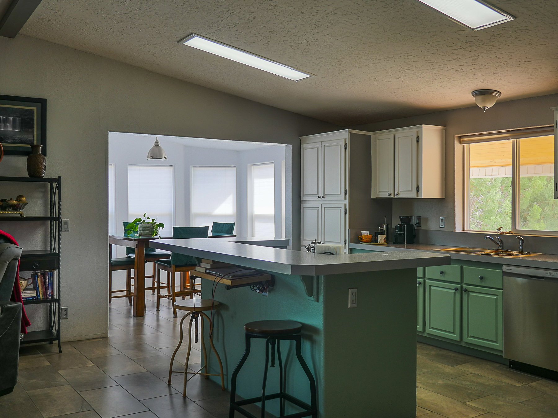 Kitchen with a kitchen island, two tone color scheme, stainless steel dishwasher, a breakfast bar area, and light countertops
