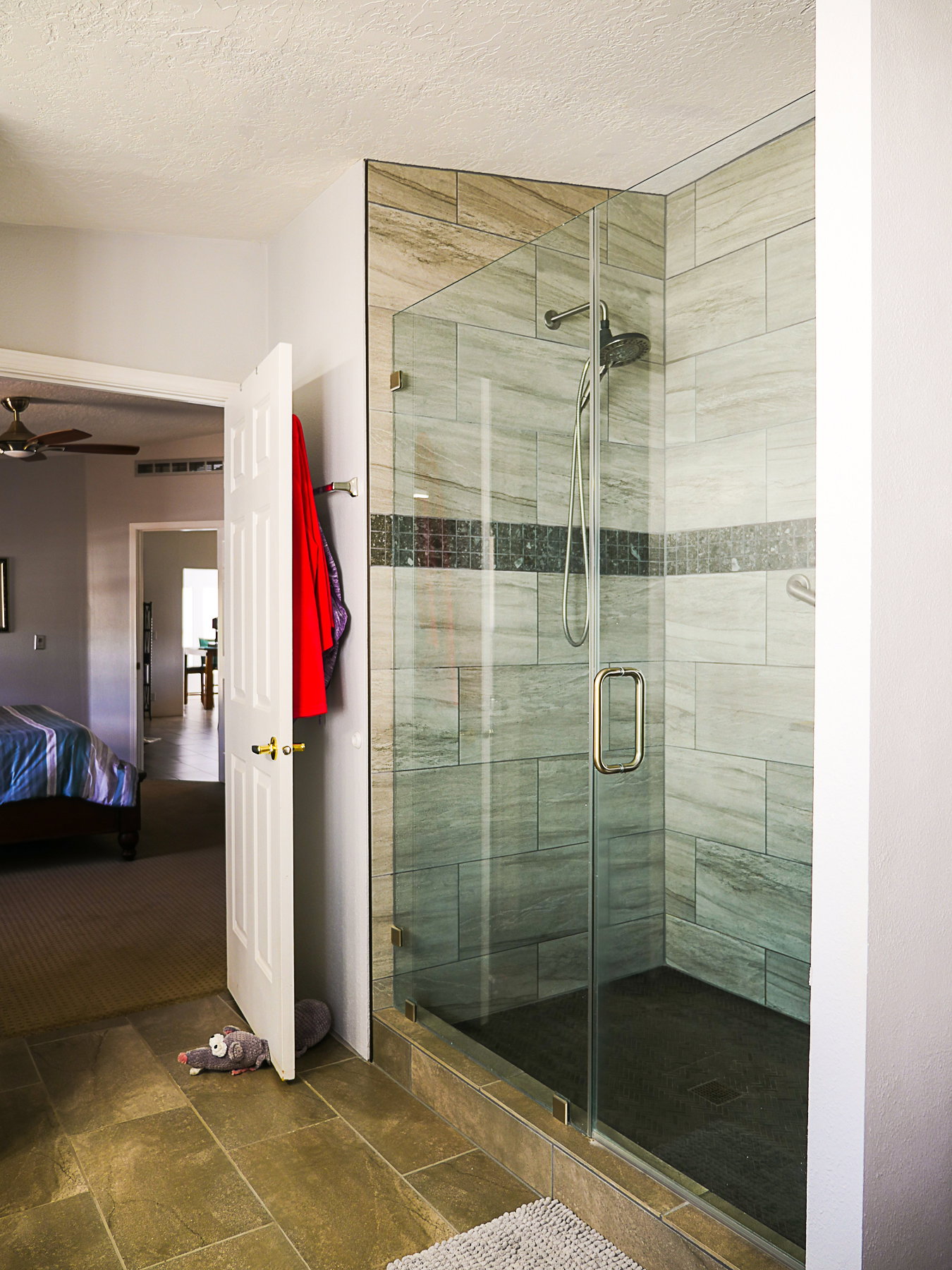 Bathroom featuring a stall shower, ensuite bath, a textured ceiling, a ceiling fan, and stone tile floors