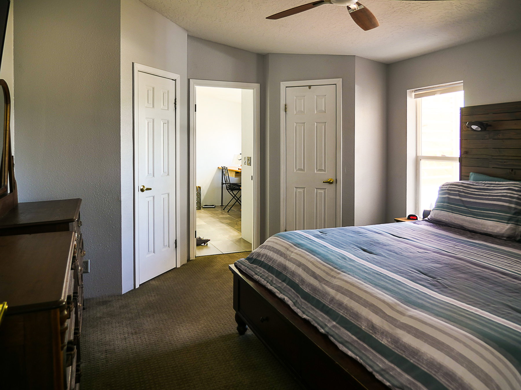 Bedroom with dark carpet, a textured ceiling, a ceiling fan, and a textured wall