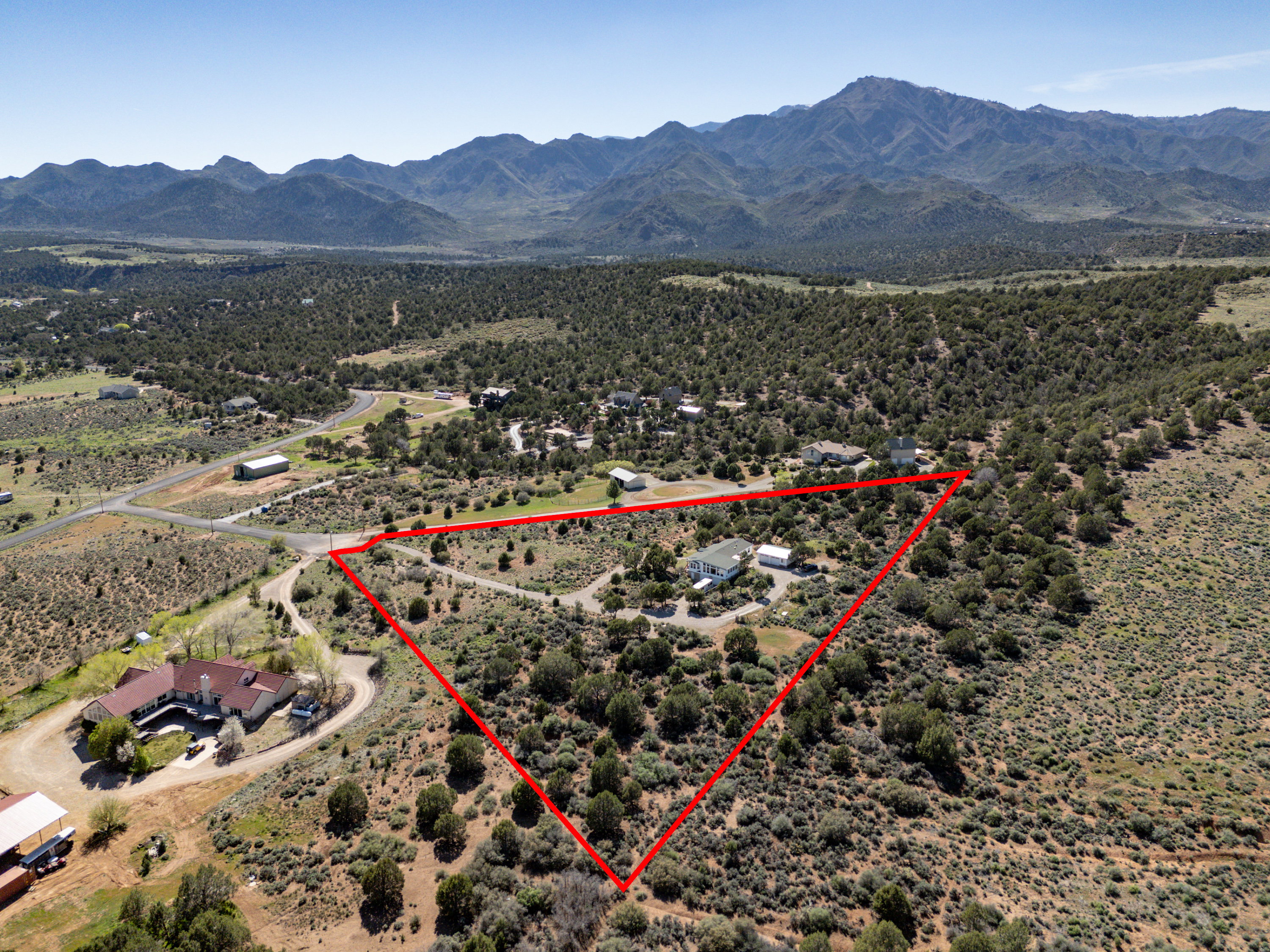Aerial view of sparsely populated area featuring property boundaries highlighted and a mountain backdrop