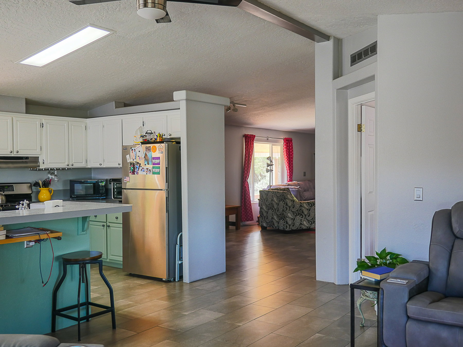 Dual tone kitchen featuring stainless steel appliances, a kitchen breakfast bar, a textured ceiling, light countertops, and two tone cabinetry
