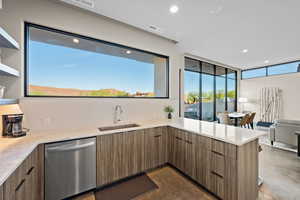 Kitchen with open floor plan, light stone countertops, stainless steel dishwasher, modern cabinets, and a peninsula