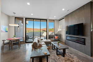 Living area with finished concrete floors, floor to ceiling windows, a large fireplace, and recessed lighting