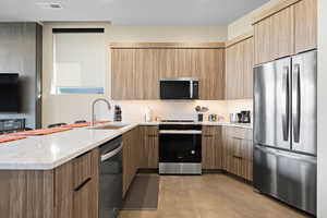 Kitchen featuring stainless steel appliances, light stone countertops, a peninsula, and modern cabinets