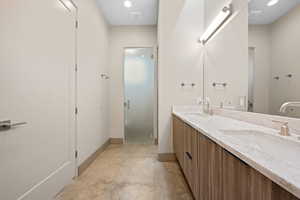 Bathroom with double vanity, unfinished concrete floors, recessed lighting, and a stall shower