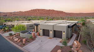 Pueblo-style home featuring a mountain view, stucco siding, driveway, an attached garage, and a residential view