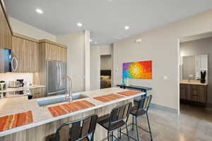 Kitchen featuring a breakfast bar, modern cabinets, a peninsula, light stone countertops, and stainless steel appliances