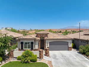 Mediterranean / spanish-style home with stone siding, a garage, driveway, stucco siding, and a mountain view