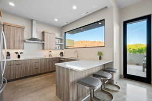 Kitchen featuring modern cabinets, concrete flooring, a breakfast bar area, a peninsula, and backsplash