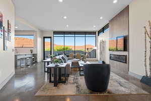 Living area with finished concrete floors, recessed lighting, expansive windows, and a tiled fireplace