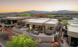 Rear view of property with stucco siding, a fireplace, a mountain view, a patio, and outdoor lounge area