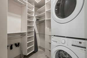 Laundry area with stacked washer and dryer and concrete floors
