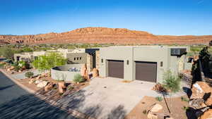 View of front of house with a mountain view, driveway, a garage, and stucco siding