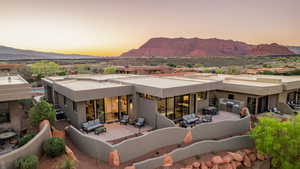 Back of property at dusk with a mountain view, stucco siding, and an outdoor living / dining area