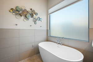 Bathroom featuring a freestanding tub, tile walls, and wainscoting