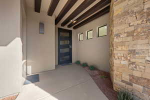 Property entrance with stucco siding, stone siding, and a patio area