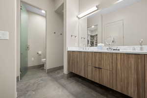 Bathroom with double vanity, concrete floors, and a spacious closet