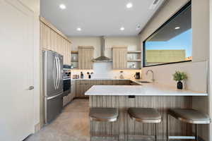 Kitchen featuring open shelves, a peninsula, a breakfast bar, stainless steel appliances, and recessed lighting