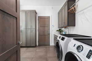 Laundry room featuring independent washer and dryer, cabinet space, and light tile patterned flooring