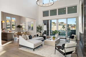 Living room with hanging lights, dark wood-style flooring, and a high ceiling