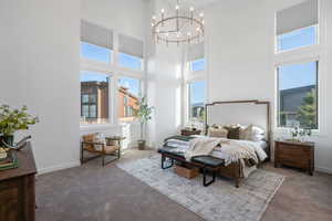 Bedroom with hanging lights, carpet flooring, and a high ceiling