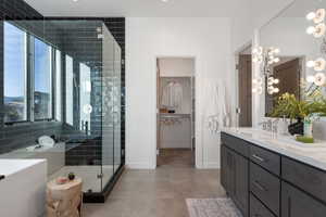 Full bath with double vanity, a spacious closet, a shower stall, and light tile patterned floors