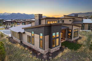 Back of property featuring stone siding, a sunroom, a chimney, and a mountain view