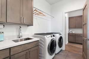 Laundry room with washing machine and dryer, dark tile patterned flooring, and cabinet space
