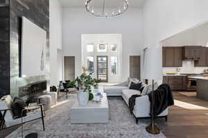 Living room featuring dark wood-style flooring, a tile fireplace, a high ceiling, and a chandelier