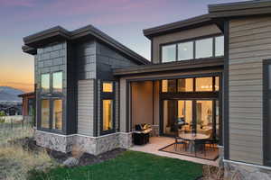 Rear view of house with stone siding and a patio