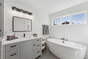 Bathroom with vanity, a freestanding tub, and light tile patterned floors