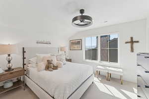 Bedroom with vaulted ceiling, light carpet, and a ceiling fan