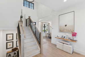 Staircase with wood finished floors, a high ceiling, and recessed lighting