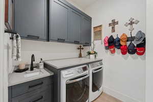 Laundry area with cabinet space, separate washer and dryer, and light wood-style flooring