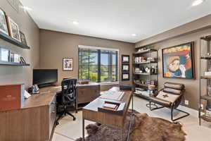 Office space with light colored carpet and recessed lighting