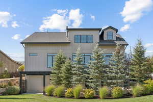 View of front of house with a shingled roof, an attached garage, and a front lawn