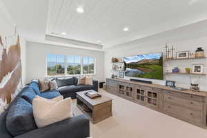 Living room with light colored carpet, recessed lighting, and a wooden tray ceiling