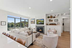 Living room featuring light wood-type flooring, a large fireplace, and recessed lighting