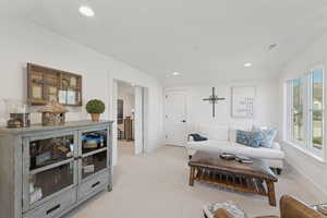 Living room featuring vaulted ceiling, recessed lighting, and light carpet
