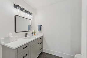 Half bath with vanity and dark tile patterned flooring